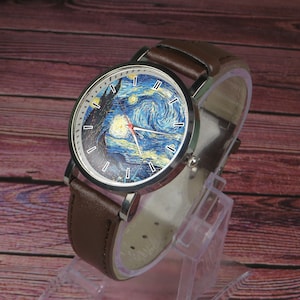May include: A brown leather wristwatch with a silver case and a white face featuring a painting of Vincent van Gogh's "Starry Night".