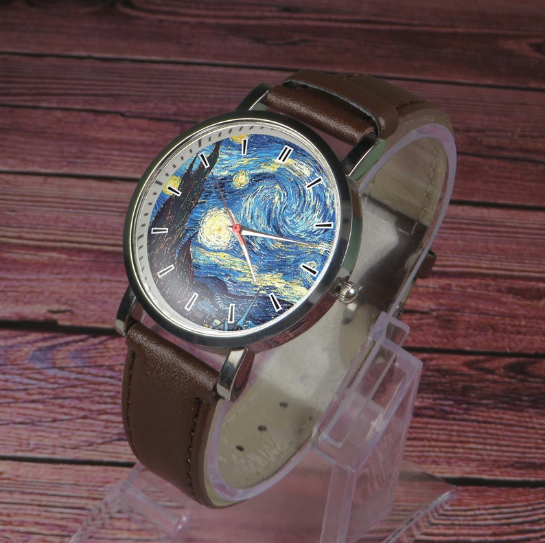 May include: A brown leather wristwatch with a silver case and a white face featuring a painting of Vincent van Gogh's "Starry Night".