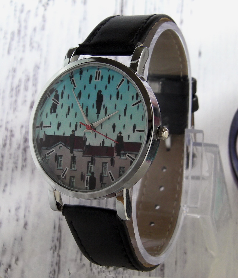 May include: A silver wristwatch with a black leather band. The watch face features a colorful image of people on a rooftop in the rain.