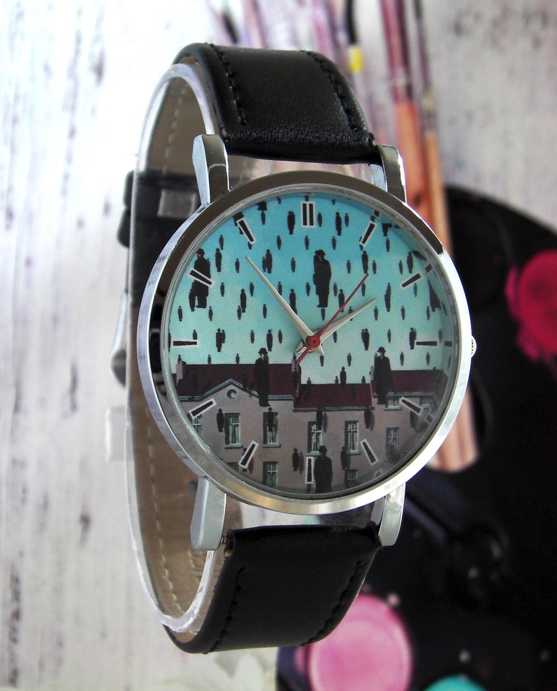 May include: A silver wristwatch with a black leather band. The watch face features a blue and white print of a painting with figures on a rooftop.