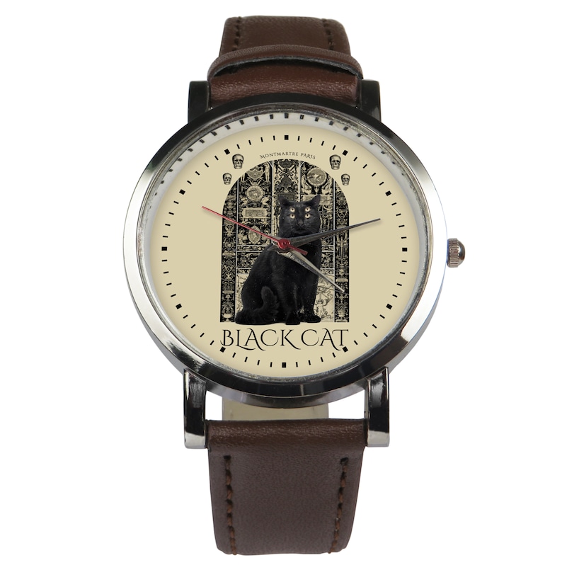 May include: A brown leather wristwatch with a silver face. The face features a black cat sitting in front of a detailed, ornate doorway. The text "BLACK CAT" is printed below the cat. The text "MONTMARTRE PARIS" is printed above the cat.
