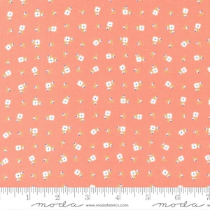 May include: A coral pink fabric with a white floral pattern. The fabric has a small white flower with a blue center. The fabric is shown with a ruler for scale.