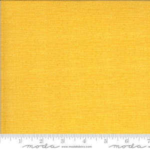 May include: A solid yellow fabric with a subtle woven texture. The fabric is shown with a ruler for scale.