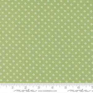 May include: Green fabric with a white repeating pattern of small crosses. The fabric is measured in inches with the text "moda" printed on the ruler.