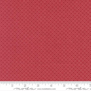 May include: Red fabric with a repeating pattern of small, light pink circles. The fabric has a ruler along the bottom edge, marked in inches. The fabric is a solid color with a subtle texture.
