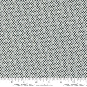May include: Close-up of fabric with a repeating geometric pattern. The design features interlocking dark blue shapes against a light beige background. The fabric has a ruler along the bottom edge, with the word "moda" printed on it.