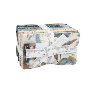May include: A stack of fabric squares tied with a white measuring tape. The fabrics feature floral patterns in shades of blue, tan, and brown. The label reads "Moda Fabrics Supplies".