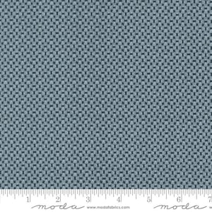 May include: A close-up of a fabric with a repeating geometric pattern in shades of blue and gray. The pattern consists of interlocking shapes, creating a textured appearance. The fabric is likely used for quilting or other craft projects.