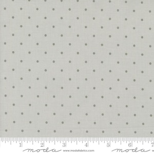 May include: A light gray fabric with a subtle pattern of small gray dots. The fabric is measured in inches with the text "moda" printed on the ruler.