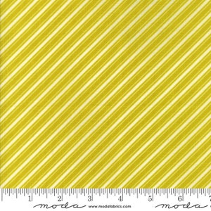 May include: A fabric swatch featuring a diagonal stripe pattern in shades of yellow and white. The stripes are evenly spaced and run across the fabric. The fabric has a textured appearance, and a ruler is visible along the bottom edge.