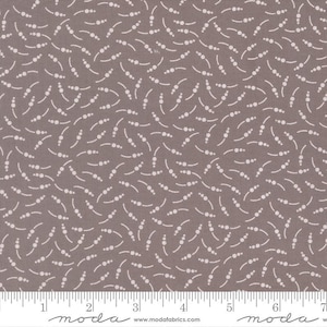 May include: Close-up of a fabric with a repeating pattern of white dots and curved lines on a muted gray background. The fabric has a ruler along the bottom edge, with measurements in inches.