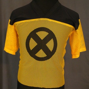 Könnte beinhalten: Gelbes und schwarzes Mesh-Trikot mit einem schwarzen X in einem Kreis auf der Vorderseite.