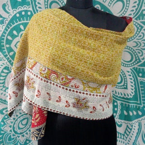 May include: A yellow and white kantha quilt scarf with a red and white floral border. The scarf is draped over a mannequin's shoulders.