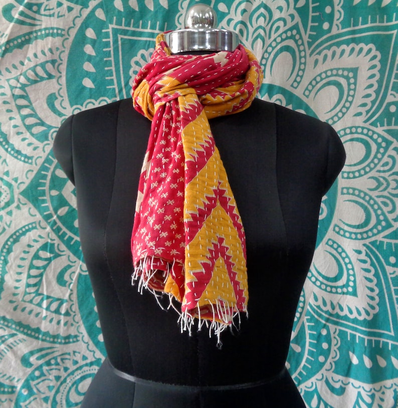 May include: A red and yellow kantha stitch scarf with a geometric pattern. The scarf is draped around a mannequin's neck.