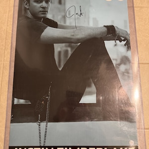 May include: A black and white poster featuring Justin Timberlake. The poster has a signature and the text "Justin Timberlake" at the bottom. The upper right corner has the initials "JT" in a stylized font.