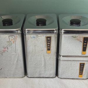 Peut inclure: Ensemble de quatre boîtes de cuisine vintage en acier inoxydable. Les boîtes ont des boutons noirs sur les couvercles et des étiquettes indiquant «SUCRE», «THÉ» et «CAFÉ». Le plus grand récipient présente un motif floral.