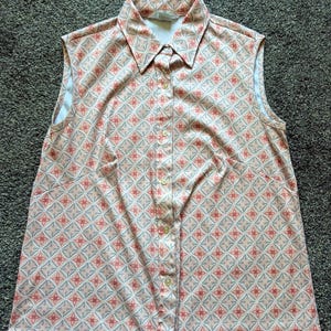 May include: A sleeveless button-up shirt with a pink and white geometric pattern. The shirt has a collar and a button closure.
