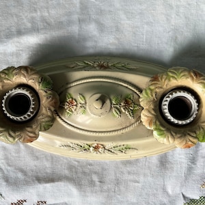 Peut inclure: Un luminaire de plafond ovale antique blanc avec deux douilles. Les douilles sont entourées de motifs floraux décoratifs dans des tons de vert et de brun.