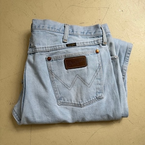 Puede incluir: Un par de pantalones vaqueros de mezclilla azul claro con un parche de cuero marr&oacute;n Wrangler en el bolsillo trasero.