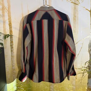 May include: A long-sleeved button-down shirt with vertical stripes in shades of red, black, and brown on a beige background.