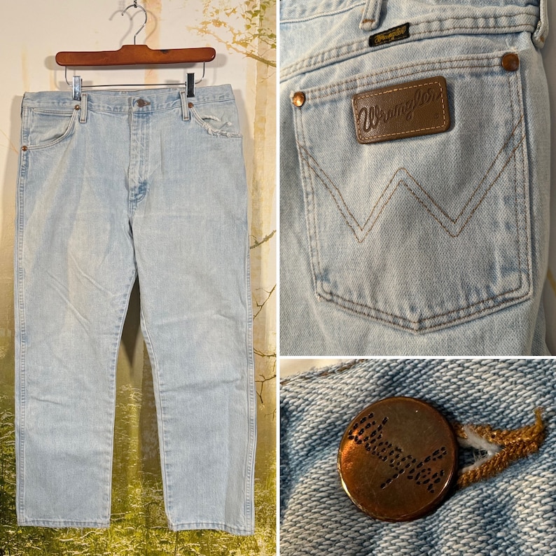 Puede incluir: Vaqueros de mezclilla azul claro con un parche de cuero marr&oacute;n Wrangler en el bolsillo trasero. Los vaqueros tienen una pierna recta y un ajuste holgado.