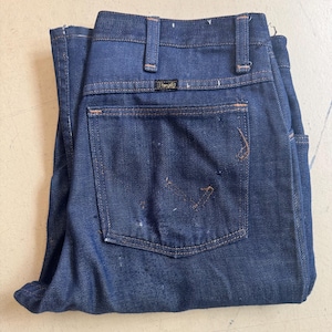 May include: A pair of dark blue denim jeans with a back pocket and a Wrangler label.