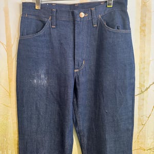 May include: A pair of dark blue denim jeans with a classic straight leg fit. The jeans have a button fly and belt loops.