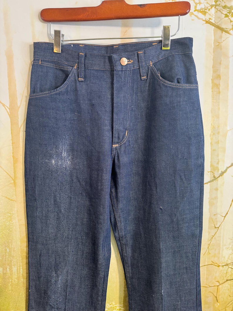 May include: A pair of dark blue denim jeans with a classic straight leg fit. The jeans have a button fly and belt loops.