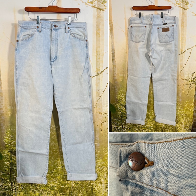 May include: Light blue denim jeans with a cuffed hem and a brown leather patch with the Wrangler logo on the back pocket.