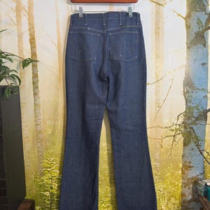 May include: A pair of dark blue denim jeans with a high waist and a wide leg. The jeans have a classic straight leg style and are made of a soft, comfortable denim.