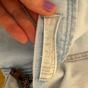 May include: Light blue denim shorts with a zipper and a white label that says "ZARA" and "Made in Morocco" in black text.