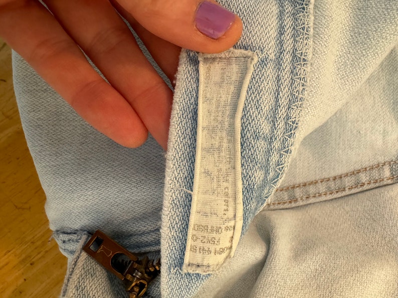 May include: Light blue denim shorts with a zipper and a white label that says "ZARA" and "Made in Morocco" in black text.