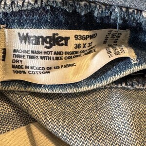 Pu&ograve; includere: Un'etichetta bianca con testo nero che recita "Wrangler 936PVD 36 x 32" e "MACHINE WASH HOT AND INSIDE OUT FIRST THREE TIMES WITH LIKE COLORS, TUMBLE DRY MADE IN MEXICO OF US FABRIC 100% COTTON".