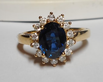 May include: A gold ring with a large blue sapphire surrounded by a halo of smaller diamonds.