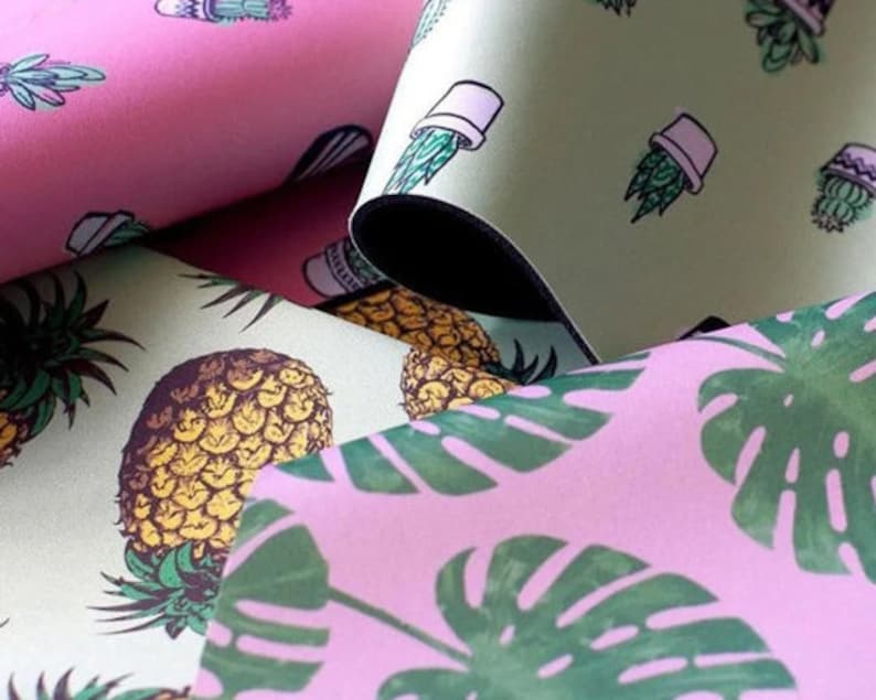 May include: Close-up of three different fabric swatches with tropical patterns. The first swatch is pink with a green cactus and a pineapple design. The second swatch is green with a white potted cactus design. The third swatch is pink with a green monstera leaf design.