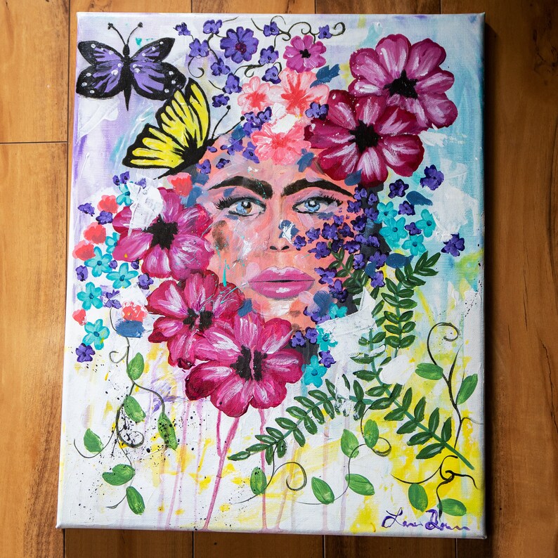 Pode incluir: Pintura acr&iacute;lica sobre tela com o rosto de uma mulher rodeado por flores e borboletas vibrantes. A obra utiliza uma paleta de rosa, roxo, azul e amarelo, com detalhes em folhagem verde. O estilo &eacute; texturizado e expressivo.