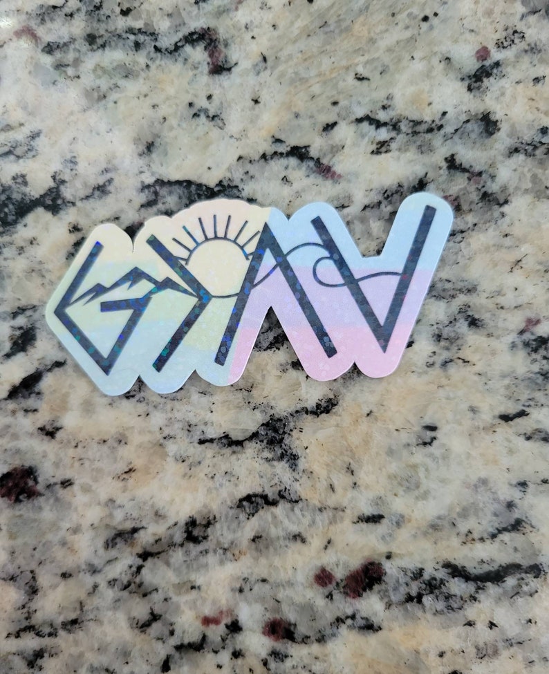 May include: A holographic sticker with a rainbow color scheme. The sticker features a mountain, sun, and wave design with the word "Grateful" written in black.