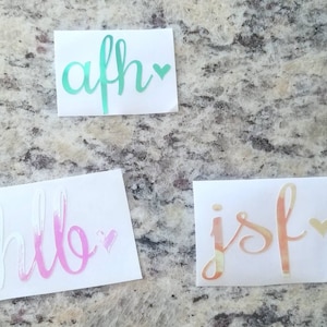 May include: Four white sticker sheets with different colored words and hearts. The words are "afh", "hello", "jsf" and each word has a small heart next to it.
