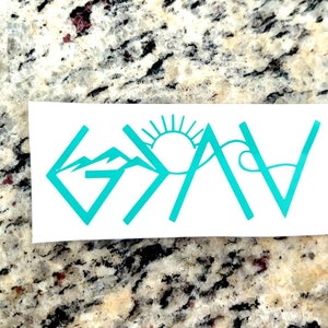 May include: A white sticker with the word "GAV" in teal, incorporating mountain, sun, and wave graphics. The design is a stylized representation of the word, with the letters formed by the graphics.