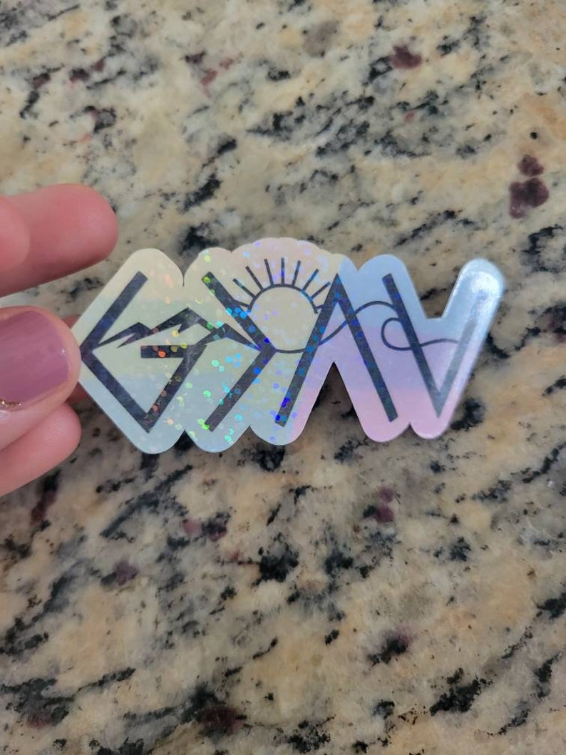 May include: A holographic sticker with a mountain range, sun, and the word "Grateful" in a stylized font.