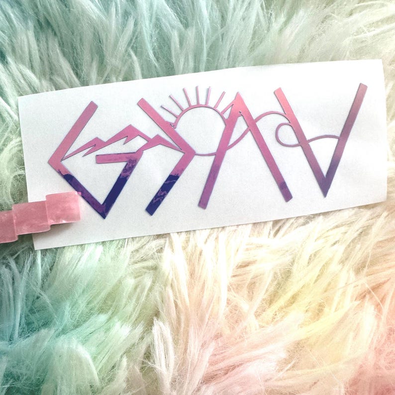 May include: A white sticker with the word "GOAV" in a gradient pink and purple color scheme. The letters are stylized with mountain and sun designs. The sticker is on a fluffy, rainbow-colored surface.