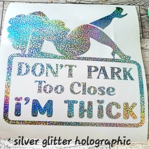 May include: Silver glitter holographic sticker with a graphic of a woman reclining on a sign that reads "DON'T PARK Too Close I'M THICK". The sticker also has the text "silver glitter holographic".