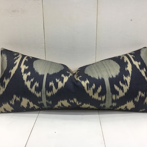 Könnte beinhalten: Ein langes, rechteckiges Kissen mit einem schwarzen und cremefarbenen Ikat-Muster. Das Kissen ist aus einem weichen, luxuriösen Stoff gefertigt.