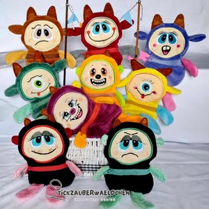 May include: Eight plush toys with different facial expressions and colors. The toys are all in a basket and have a zipper on their backs. The toys are all different colors, including red, blue, green, yellow, orange, and purple.
