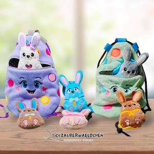 May include: A collection of colorful, plush bunny-themed drawstring bags and small stuffed bunny toys. The bags are purple, blue, and green, with embroidered faces and details. The bunnies are in various colors, including brown, blue, and pink.