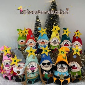 Peut inclure: Douze lutins en peluche avec des visages brodés et des étoiles sur leurs chapeaux. Chaque lutin porte un numéro différent de 1 à 12 sur son étoile. Les lutins sont disposés en demi-cercle devant un sapin de Noël.