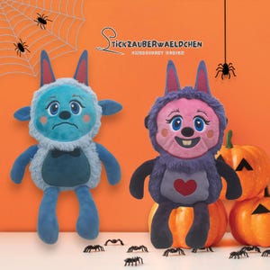 May include: Two plush monster dolls with large eyes, one blue and one purple, sit on an orange background with pumpkins and spiders. The blue doll has a sad expression, while the purple doll smiles. The dolls have long ears and are designed for Halloween.