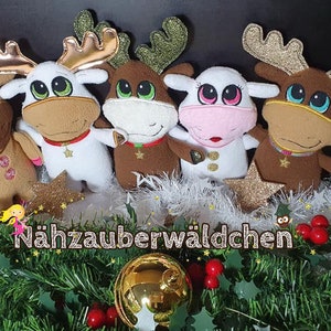 May include: Five plush reindeer toys with sparkly gold antlers and big eyes. The reindeer are brown, white, and pink. They are arranged in a row on a bed of white and green garland. The text "Nähzauberwäldchen" is visible at the bottom of the image.