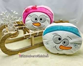 May include: Two plush snowman ornaments with embroidered faces, one with a pink hat and the other with a blue hat, sitting in a wooden sled.
