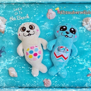 May include: Two plush seal toys, one white with colorful polka dots and one blue with a red and white striped belly, are floating in a blue pool with bubbles. The text "Let's Go To The Beach" is at the top of the image.